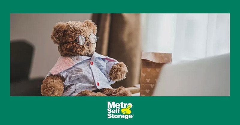 Photo of teddy bear sitting on desk near laptop
