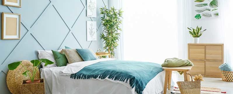 A clean, organized bedroom with a bed, shelving unit, and decorative plants
