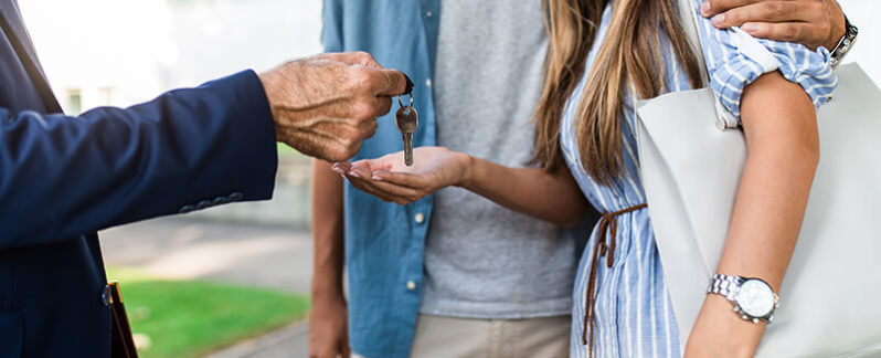 Realtor handing couple the keys to their new home.