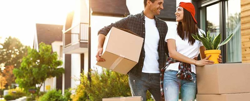 Man and woman holding moving boxes and plants.