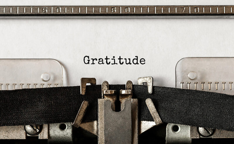 A typewriter remains motionless after typing the word "gratitude" on a piece of paper