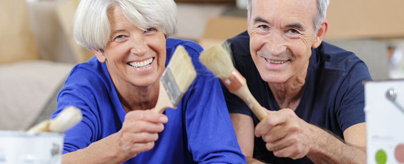 Two seniors holding paint brushes, ready to remodel their home
