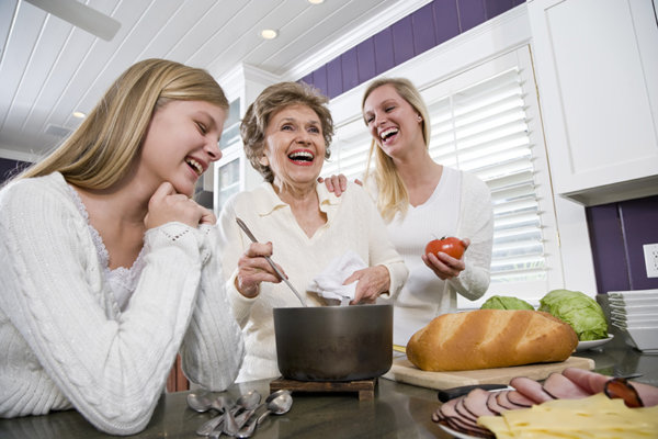 smiling mom with adult daughters cooking in family kitchen