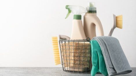 Basket of cleaning supplies on concrete floor.