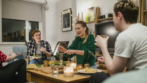 Four roommates gather around a table to share a meal.