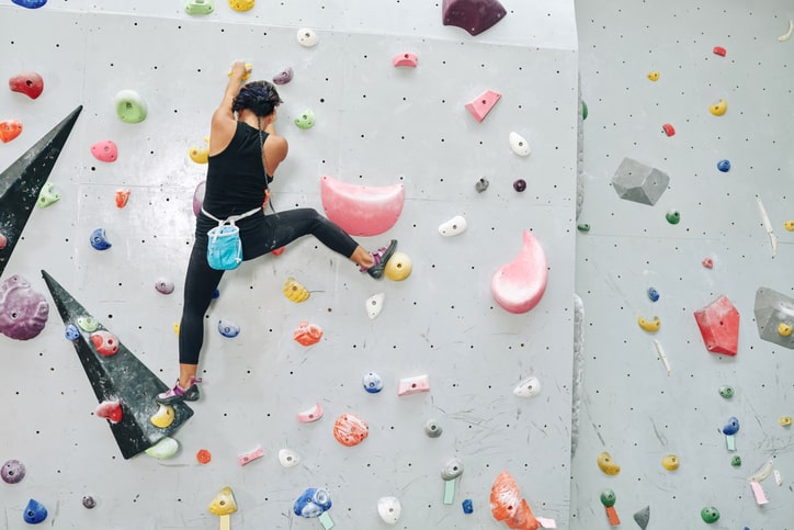 Woman rock climbing at climbing gym.