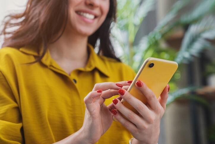 Woman smiling while typing on a cellphone.