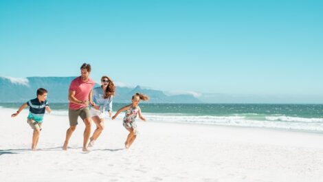 Familly happily running along the beach together.