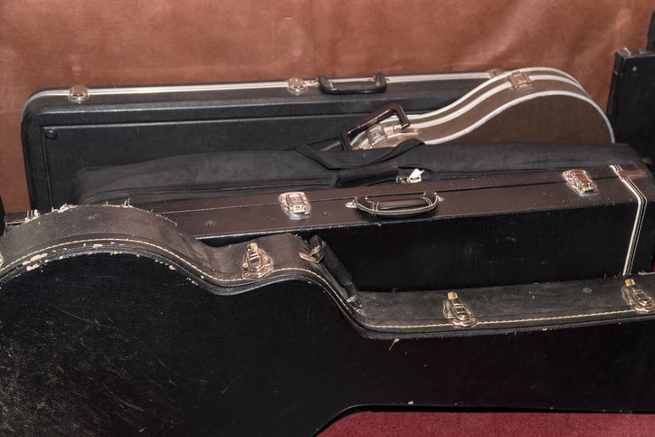 Hard shell guitar cases lined up on the floor. 