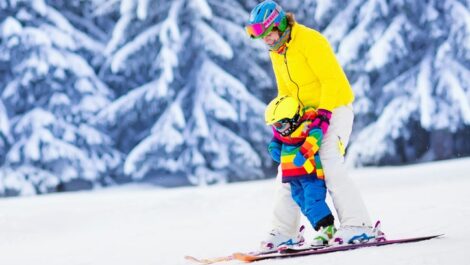 Mother helping young child learn how to ski.