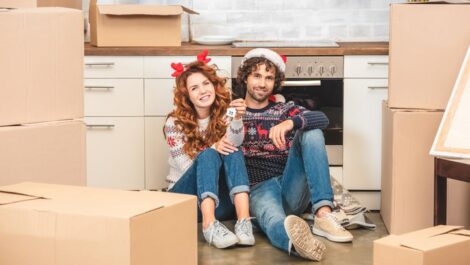 Couple smiling around boxes while wearing festive attire.
