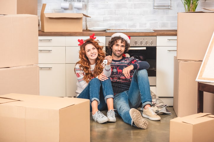 Couple smiling around boxes while wearing festive attire.