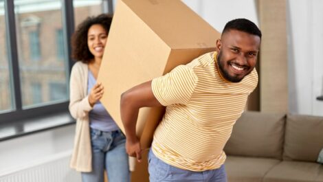 Black couple carrying a large moving box together