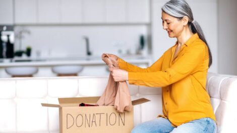 Mature woman putting clothing in donation box.