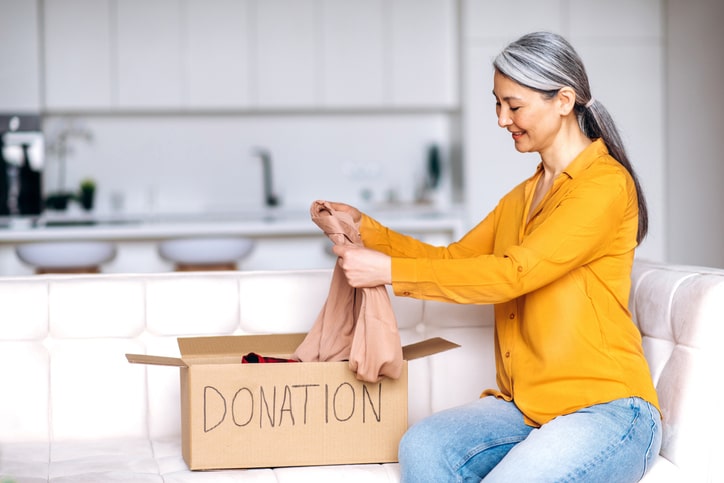 Mature woman putting clothing in donation box.