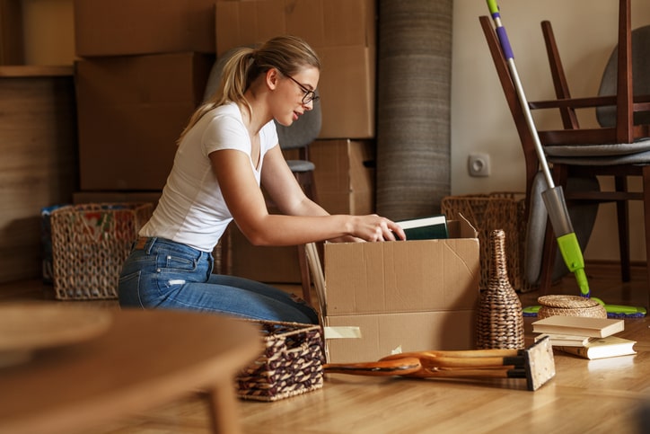 young woman packing books in a box.