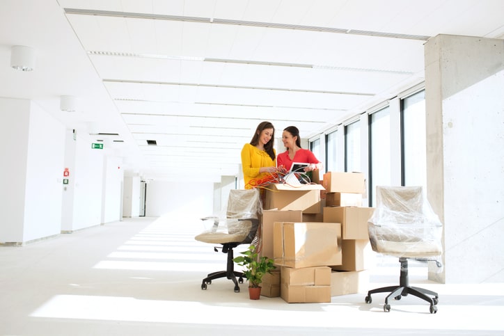 Women unpacking office supplies in new office.