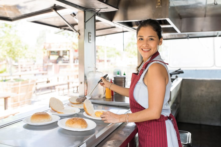 female food truck owner assembling burgers.