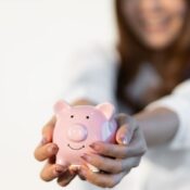 Woman with glitter manicure holding a pink piggy bank