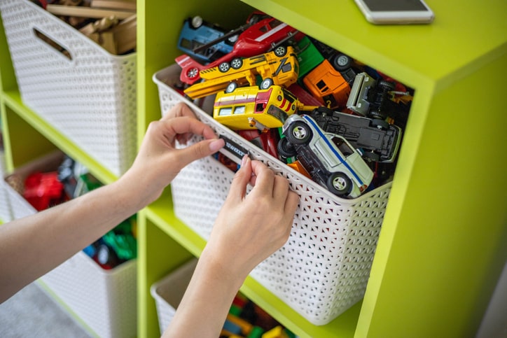 Mother labeling toy bin on a modular shelf