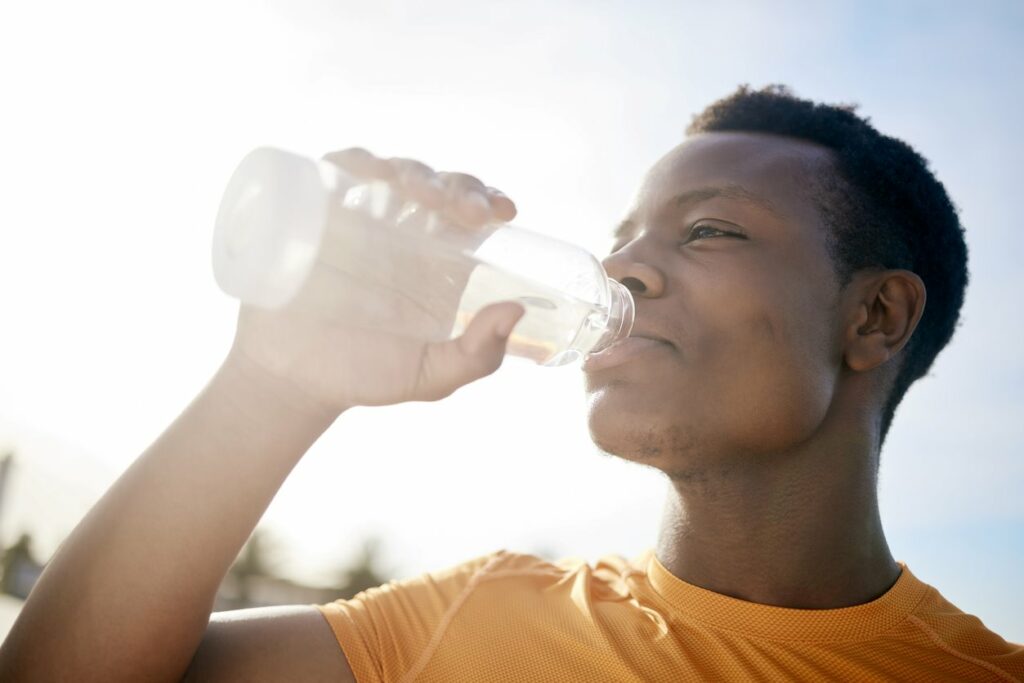 A man drinking from a bottle of water in the sun