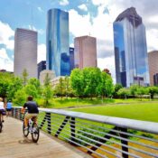 A man and a woman riding their bikes across a bridge in Houston, TX