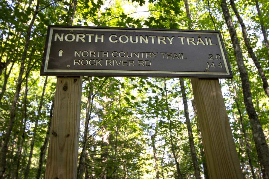 A sign in the forest that reads "North Country Trail," with the distance to North Country Trail and Rock River Road below.