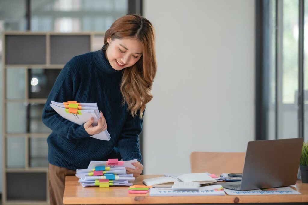 Teacher smiles while grabbing organized papers with colorful clips 
