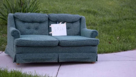 A couch sitting on the sidewalk with a sign that says “free”