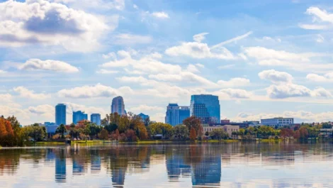 The Orlando skyline with water in the foreground and trees turning orange