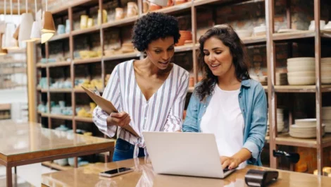 Two women work at a laptop in a small shop