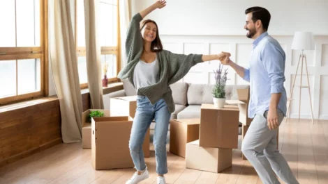 A young couple dancing in their living room, surrounded by boxes