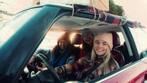 Friends in winter gear smiling in car