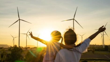 A woman and her daughter in front of some windmills.